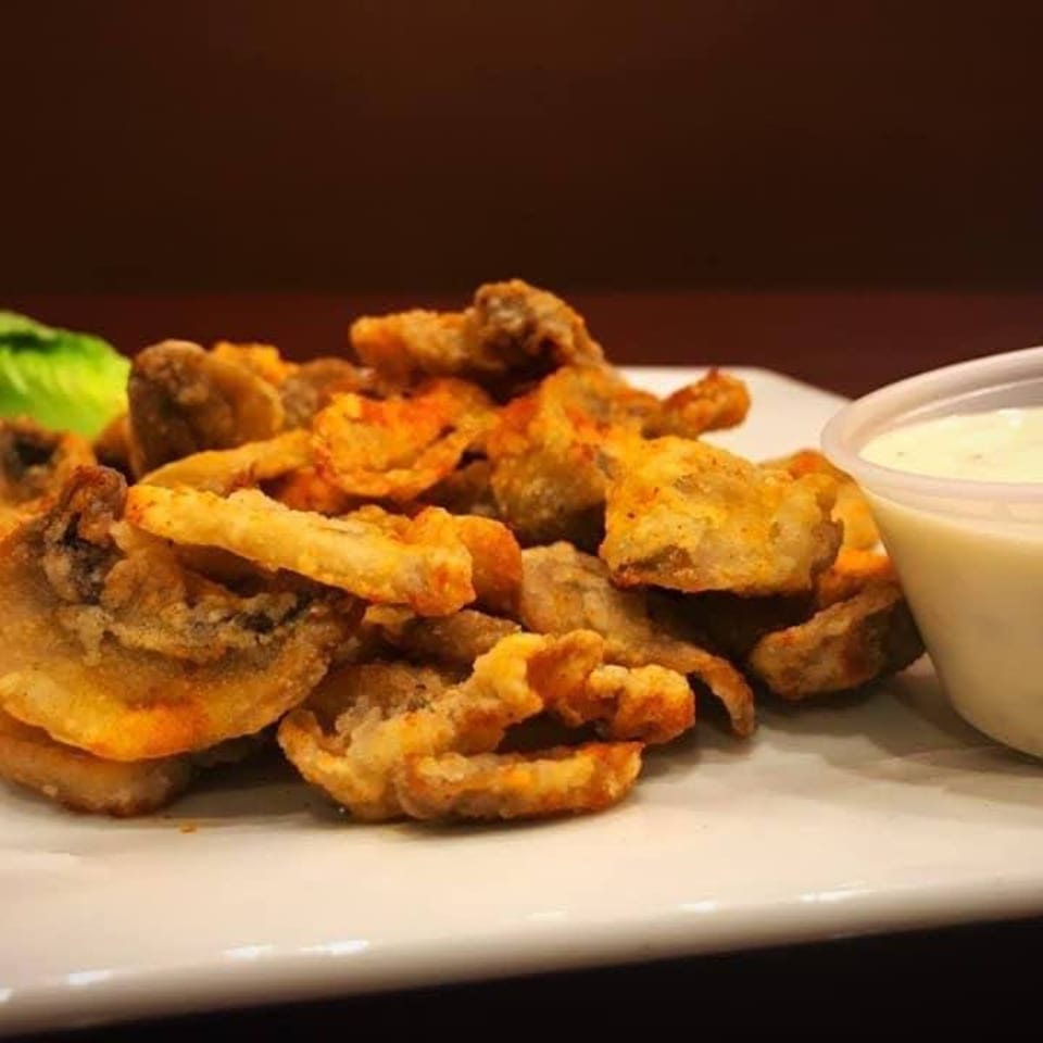 Crispy fried mushrooms with a side of creamy dipping sauce on a white plate at Leo's Asian Bistro.