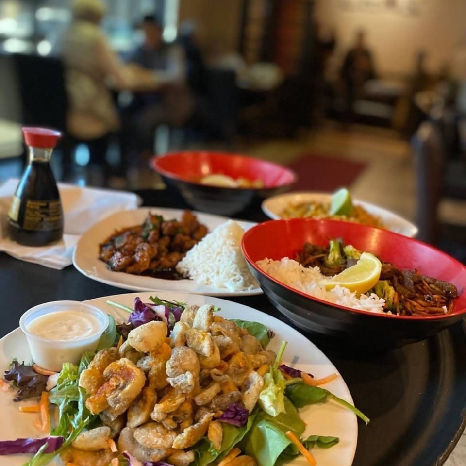 Table at Leo's Asian Bistro with multiple Asian-fusion dishes, including fried calamari salad.