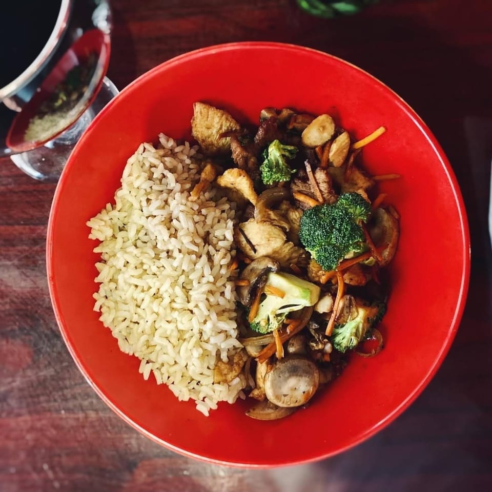 Leo's Asian Bistro's stir-fry with chicken, broccoli, mushrooms, and rice in a red bowl.